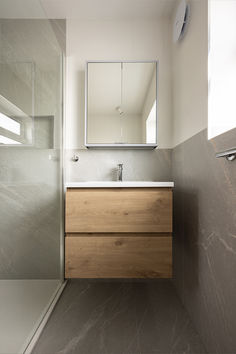 a bathroom with a sink, mirror and shower stall in it's own area