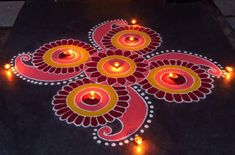 candles are lit on the ground to light up an intricate rangolite design for diwaling