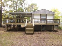 a house in the woods with stairs leading up to it's porch and deck