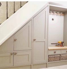 an under the stairs storage area with drawers and cupboards in grey painted wood tones