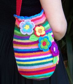 a woman wearing a colorful purse with flowers on it's side and her hand in her pocket