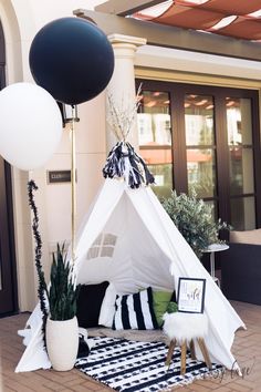 a teepee tent sitting on top of a black and white rug next to a potted plant