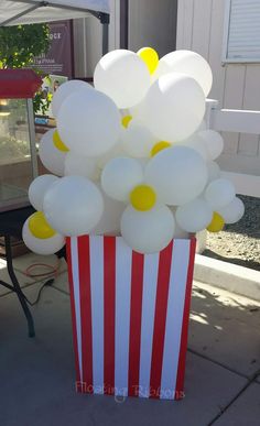 a popcorn box filled with white and yellow balloons