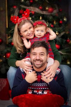 a man and woman holding a child in front of a christmas tree