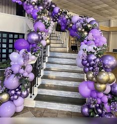 purple and gold balloons are hanging down the stairs