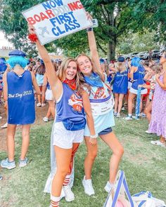 two girls holding up a sign in front of a crowd