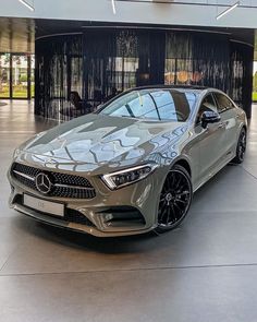 a silver mercedes cla is parked in a showroom