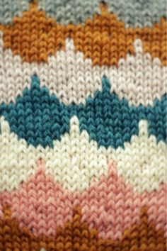 a knitted blanket with multicolored stripes on the top and bottom, close up