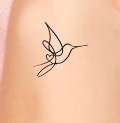 a small tattoo on the back of a woman's shoulder with a bird flying above it