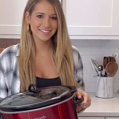 a woman holding an electric pressure cooker in her hands and smiling at the camera