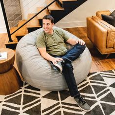 a man sitting on a bean bag chair in the middle of a living room with stairs