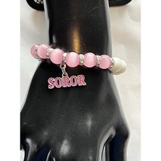 Beautifully Made Single Bracelet Of Pink, Green And White Natural Cat's Eye Agate Beads With Clear Rhinestone Accent Pieces Throughout. This Design Features A Dangling Charm That Has The Word Soror, Done In Pink Enamel Letters. It Also Features One Charm On The Bracelet Which Has Aka Embossed Into The Metal On Both Sides And Is Accented With Pink And Green Enamel Lettering. This Is A Very Special Design That Is Sure To Become A Favorite! This Bracelet May Be Worn Alone Or Mixed And Matched With Pink Crystal Bracelet With Letter Beads And Round Beads, Pink Crystal Bracelet With Letter Beads, Personalized Pink Spiritual Bracelets, Personalized Pink Spiritual Bracelet, Spiritual Pink Personalized Bracelets, Spiritual Personalized Pink Bracelets, Spiritual Personalized Pink Bracelet, Personalized Pink Spiritual Charm Bracelet, Pink Letter Beads Name Bracelet