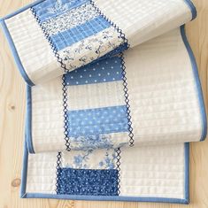 three blue and white quilts stacked on top of each other in front of a wooden table