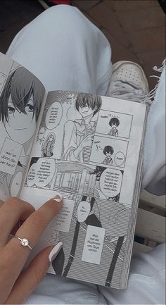 a person holding an open comic book in their hand with the pages showing anime characters