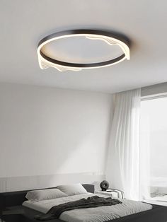 a modern bedroom with white walls and flooring, including a bed that has a circular light fixture on the ceiling