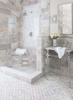 a white bathroom with marble walls and floor