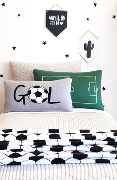 a bed with black and white pillows on top of it next to a green pillow