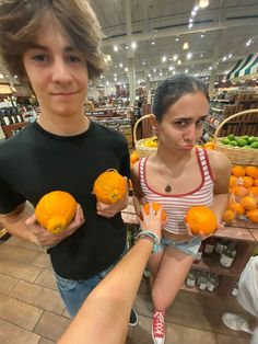 two young people holding oranges in their hands