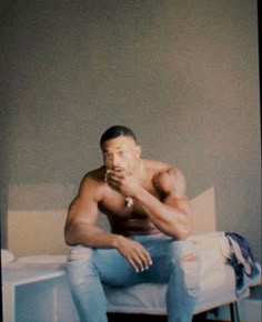 a shirtless man sitting on top of a bed