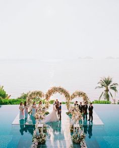 a wedding ceremony on the edge of a pool with an ocean view in the background