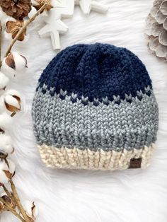 a blue and white knitted hat sitting on top of a pile of cotton flowers