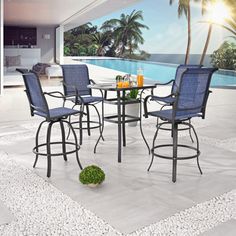 an outdoor dining set with blue chairs and a white table next to a swimming pool