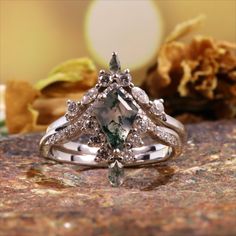 an engagement ring with a green and white diamond in the center on top of a rock