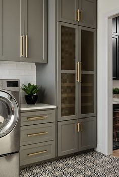 a washer and dryer in a room with gray cabinets, tile flooring and white walls