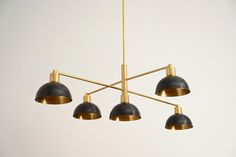 a chandelier with five black shades hanging from it's brass frame and four gold colored lights