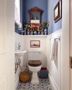 a white toilet sitting in a bathroom next to a sink under a window with flowers on it