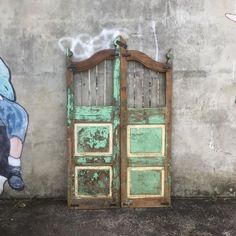 an old wooden door is painted on the side of a concrete wall with a painting of a child holding a teddy bear