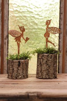 two wooden stumps with metal fairy figurines on them