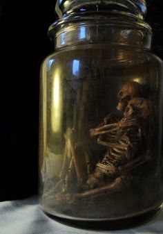 a glass jar filled with skeletons sitting on top of a table