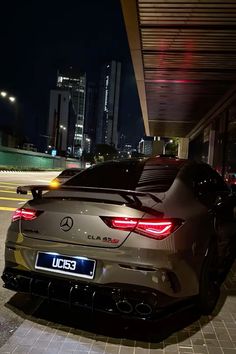 the rear end of a car parked in front of a building at night with its lights on