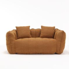 a brown couch sitting on top of a white floor next to two pillowed pillows