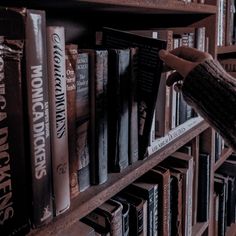 a person reaching for books on a book shelf