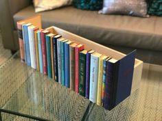 a row of books sitting on top of a glass table in front of a couch