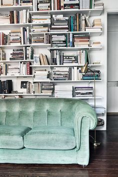 a couch sitting in front of a bookshelf filled with lots of books on it