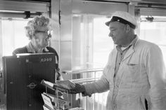 black and white photograph of two people standing in front of a computer screen on a boat