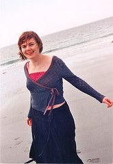 a woman standing on top of a beach next to the ocean