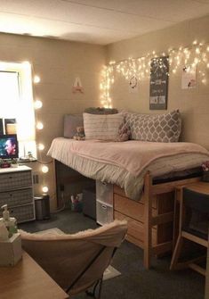 a bedroom with a bed, desk and chair in the corner is lit up by fairy lights