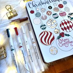 a notebook with christmas ornaments on it next to some pens