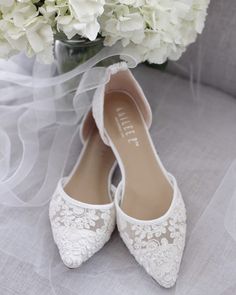 the bride's wedding shoes are adorned with white lace and pearls, along with a bouquet of hydrangeas