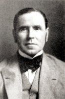 an old black and white photo of a man in a suit with a bow tie