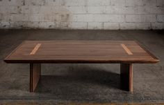 a wooden table sitting on top of a cement floor next to a white brick wall