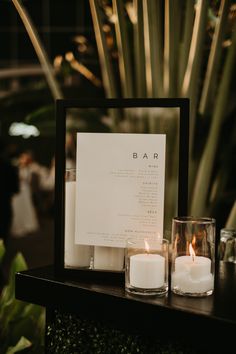 two candles are sitting on a table next to a menu