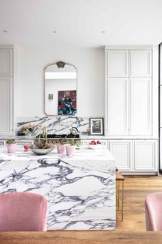 a kitchen with marble counter tops and pink chairs