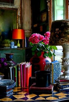 a table topped with lots of books next to a lamp