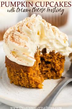 pumpkin cupcakes with cream cheese frosting are on a white plate next to a fork