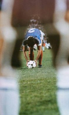 a man bending over to pick up a soccer ball